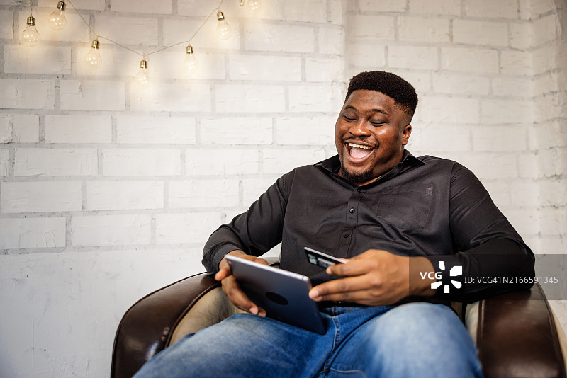 快乐的超重男子在沙发上购物图片素材