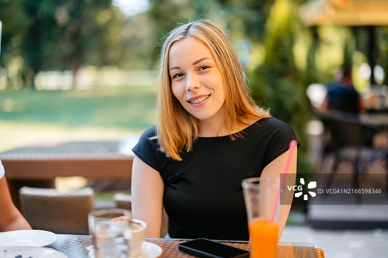 年轻女人在户外咖啡馆喝咖啡和果汁图片素材