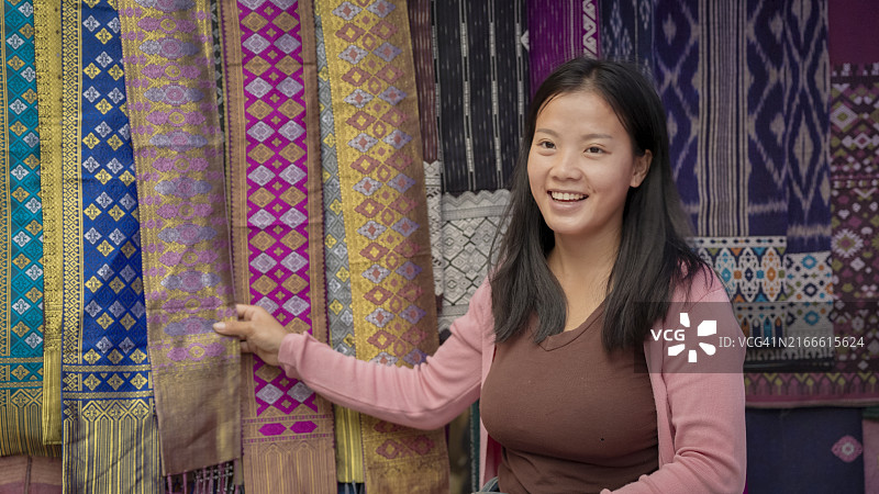 老挝琅勃拉邦：早市上售卖传统纺织品的年轻女孩图片素材