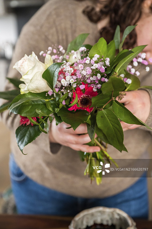 棕色卷发女人手捧鲜花室内竖版图片素材