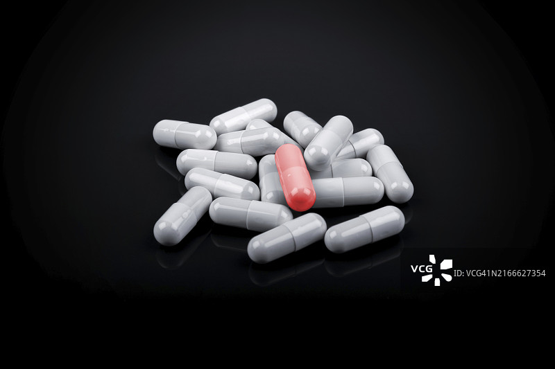 黑色背景下白色药丸之间的红色药丸图片素材