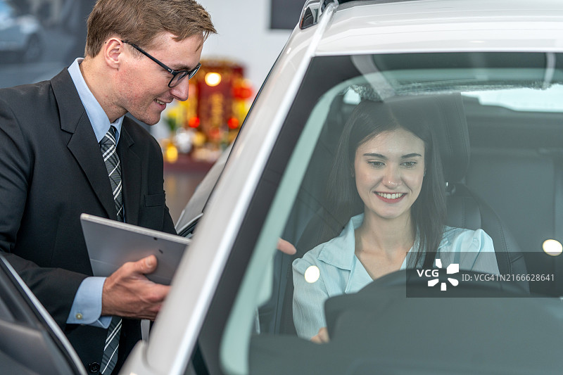 汽车销售员在展厅向女顾客介绍汽车图片素材