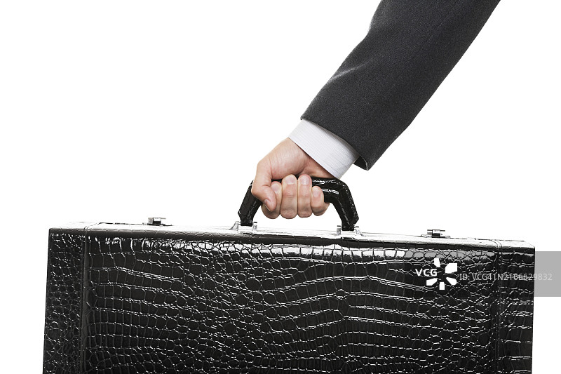 穿着黑色西装，手提大旅行箱的商人图片素材