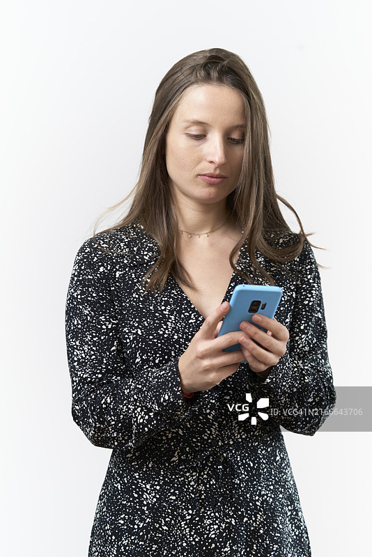 穿连衣裙的女子惊讶地看着手机，白色背景图片素材