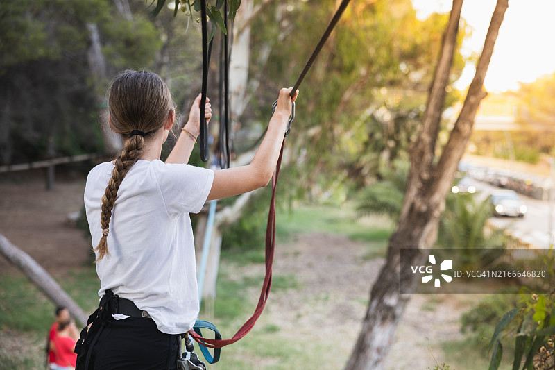 年轻女子参与户外探险公园活动，展现了户外乐趣、冒险和年轻人的自信图片素材