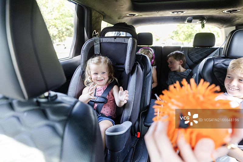 女童笑着伸手去拿玩具球，她看不见的父母递给她图片素材