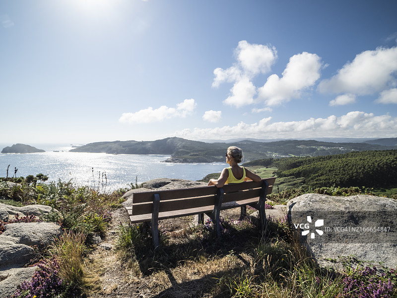 坐在长椅上欣赏卢戈海岸海景和悬崖景观的女人，加利西亚自治区图片素材