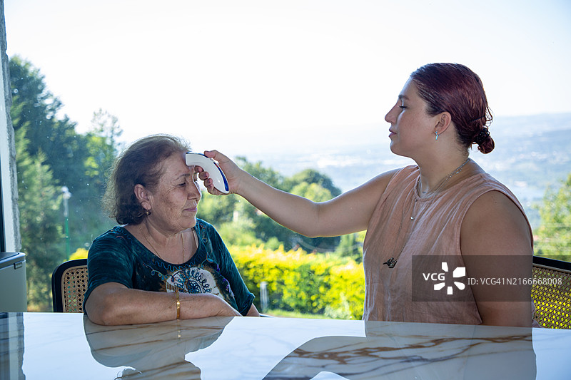 年轻女性正在测量年长女性的体温图片素材