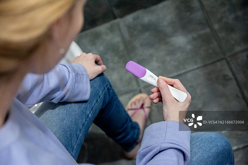 在浴室手持验孕棒的女人特写图片素材