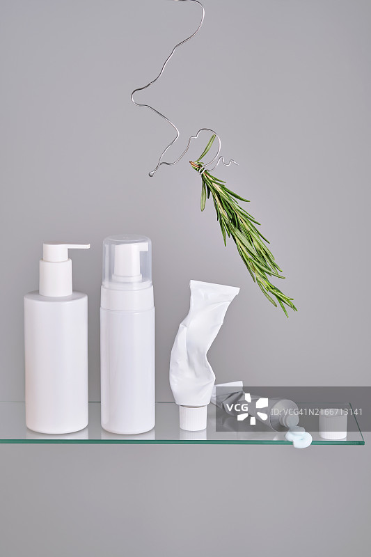 浴室玻璃架子上带有迷迭香的各种面部和身体护理产品图片素材