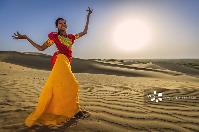 快乐的印度女孩在沙丘上跳舞，印度沙漠村庄图片素材