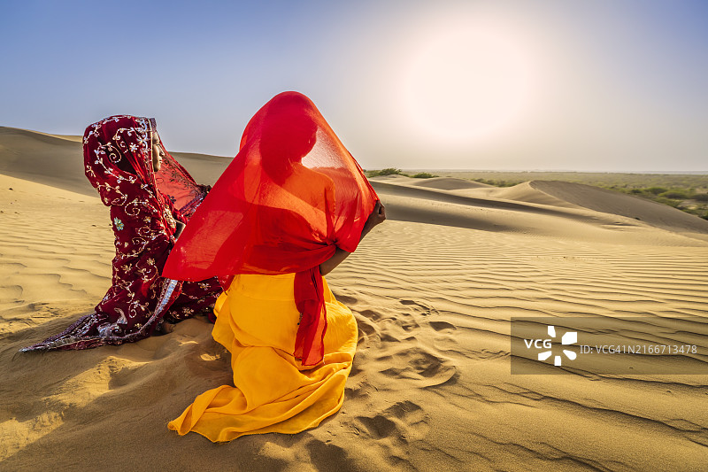 沙漠村庄沙丘上看日落的两位印度女孩图片素材