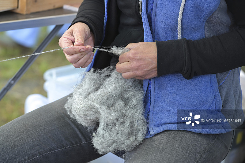 在德国工艺品市场，女人纺灰色羊毛线的手（焦点选择）图片素材