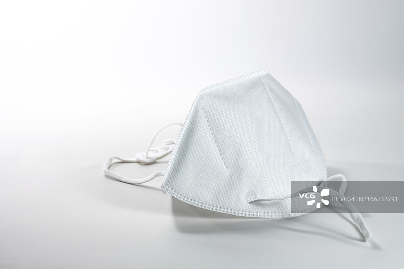 在冠状病毒大流行期间，需要使用FFP2医用口罩，以防止新冠病毒感染，白色灰色背景，具有复制空间，选择性聚焦，窄景深图片素材