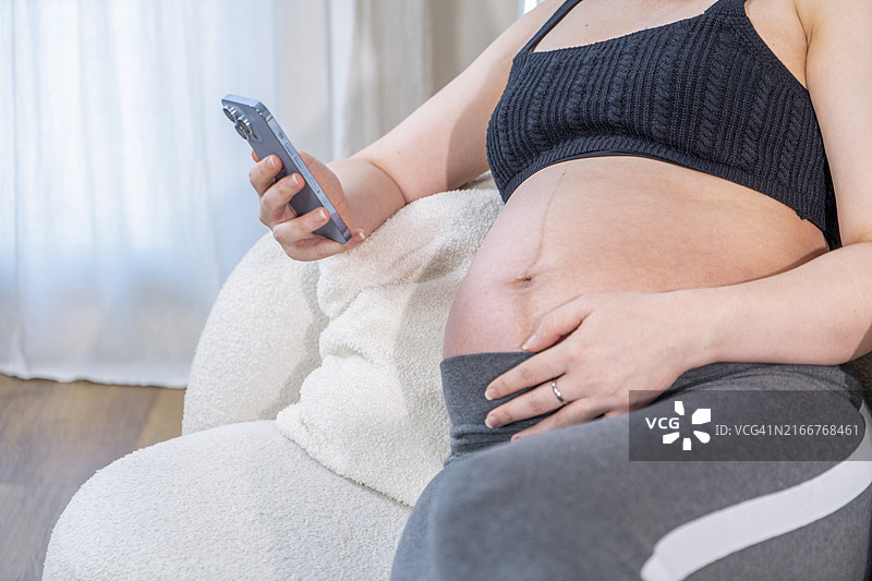 坐在沙发上使用手机的孕妇图片素材