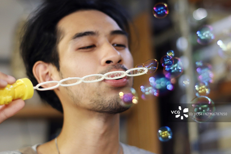 快乐无忧的概念：年轻男子在户外吹肥皂泡图片素材