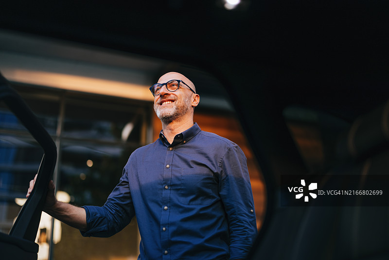 戴眼镜的商务男人下车微笑图片素材