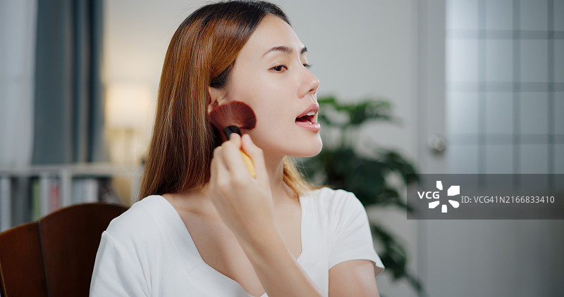 亚洲女性在家对镜化妆图片素材