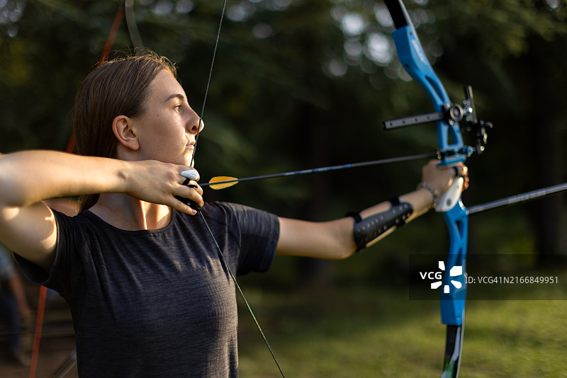 在训练场上用反曲弓练习射箭的少女图片素材