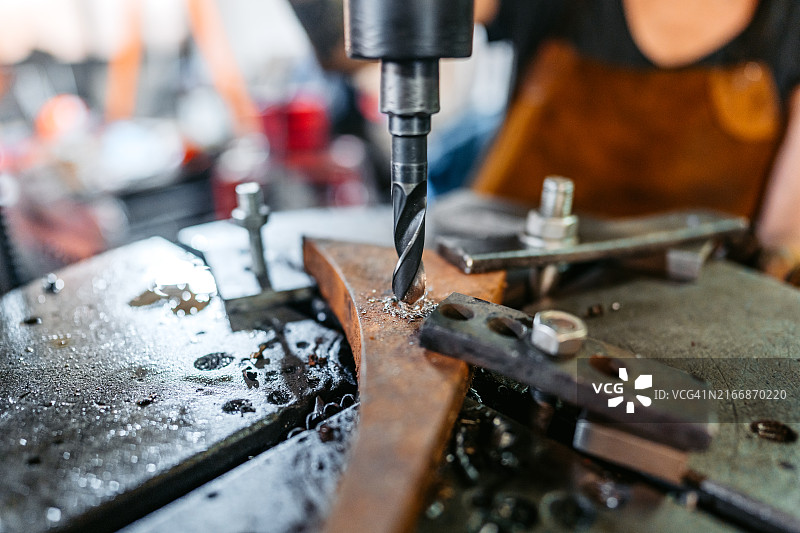 金属车间内，钻床在木头上钻孔图片素材