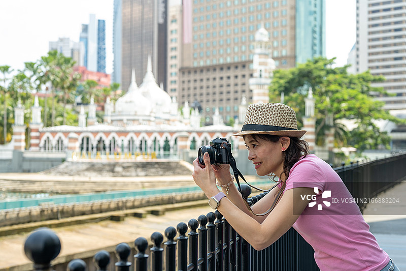 在吉隆坡占美清真寺前拍照的亚洲女性游客图片素材