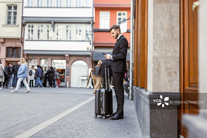 早上在街上提着行李箱等待的商人图片素材