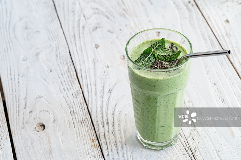 含新鲜叶类蔬菜、水果、香草和奇亚籽的绿色冰沙图片素材