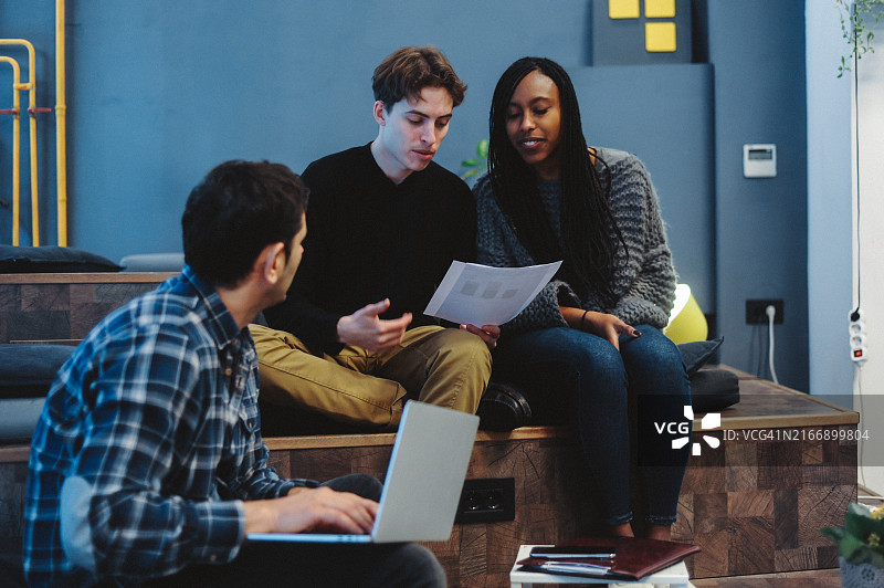 年轻专业人士在傍晚工作期间进行协作讨论图片素材