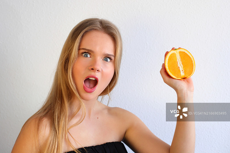 手拿橙色柑橘的年轻白人金发女孩，健康理念，西班牙图片素材