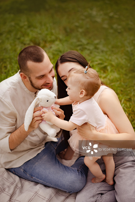 年轻家庭与小女儿在绿草地上图片素材