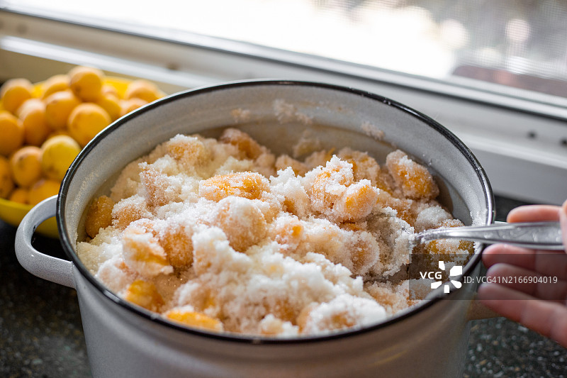 一位女士在搪瓷锅里搅拌裹着糖的杏子图片素材