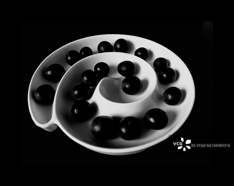 黑色背景下白碗中黑橄榄的俯视图图片素材
