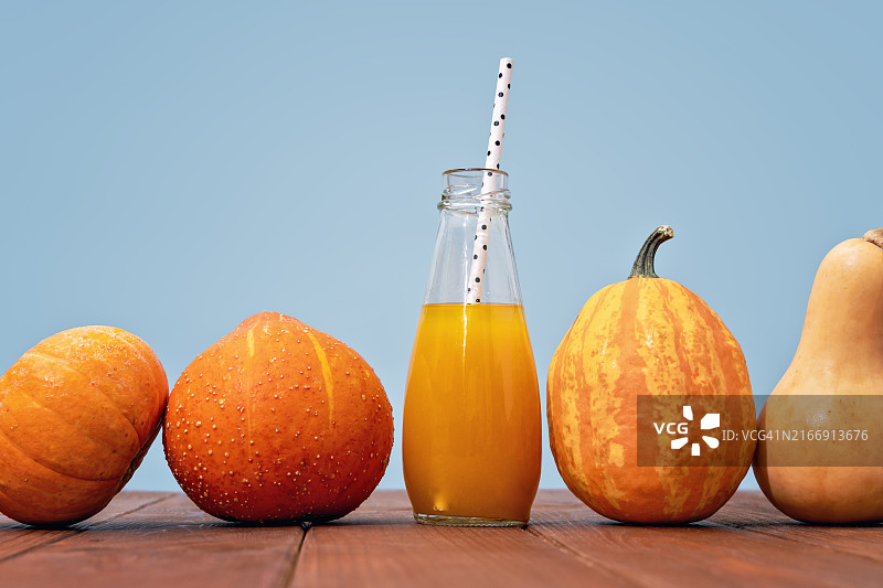 橙汁南瓜冰沙瓶与蓝色背景图片素材