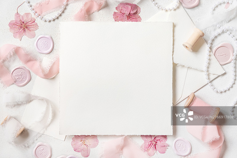 粉色装饰、印章和丝带旁的卡片，白色桌面，婚礼模型图片素材