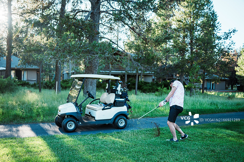 男子在高尔夫球场上打球，球车在前图片素材