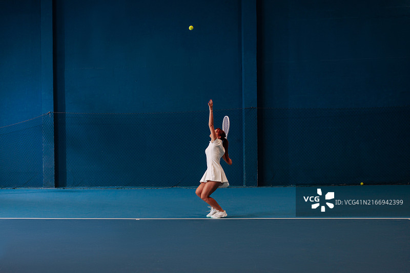 女子网球运动员在室内球场发球图片素材