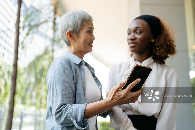 混血女商业同事在移动设备上协作图片素材