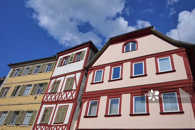 蓝色多云天空下的三栋彩色半木结构房屋，德国巴伐利亚图片素材