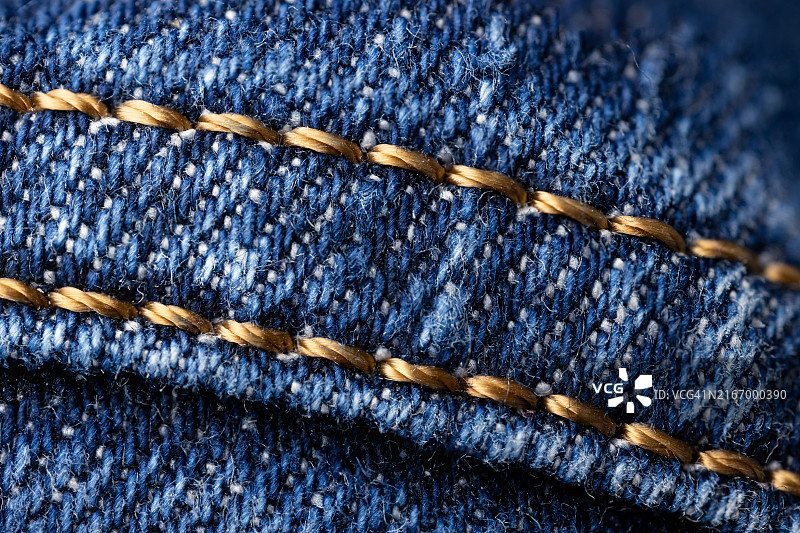 蓝色牛仔布纹理背景与黄色缝线图片素材