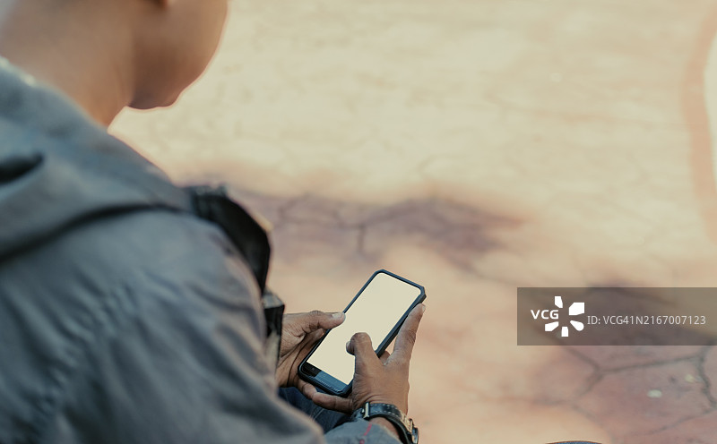 特写：在户外用手机发短信，在草地上查看手机图片素材