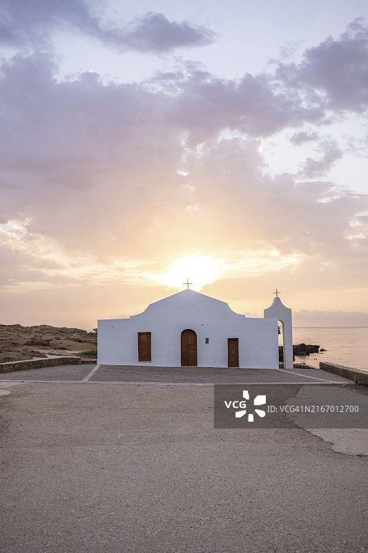 典型的希腊建筑风格白色小教堂,位于熔岩石上,被地中海和日出所环绕。阿吉奥斯·尼古拉斯教堂,希腊爱奥尼亚群岛,欧洲图片素材