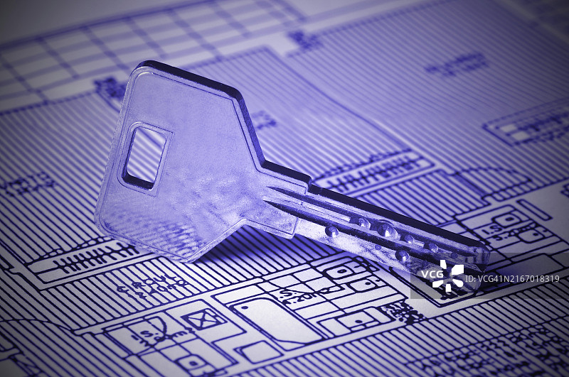 一把钥匙放在房屋蓝图上。整体图像色调为蓝色，角落有渐晕效果图片素材