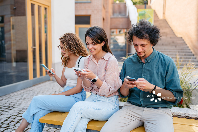 在匈牙利布达佩斯，三个朋友坐着玩手机图片素材