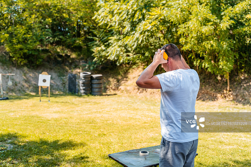 中年男子在户外射击场戴防护耳罩图片素材