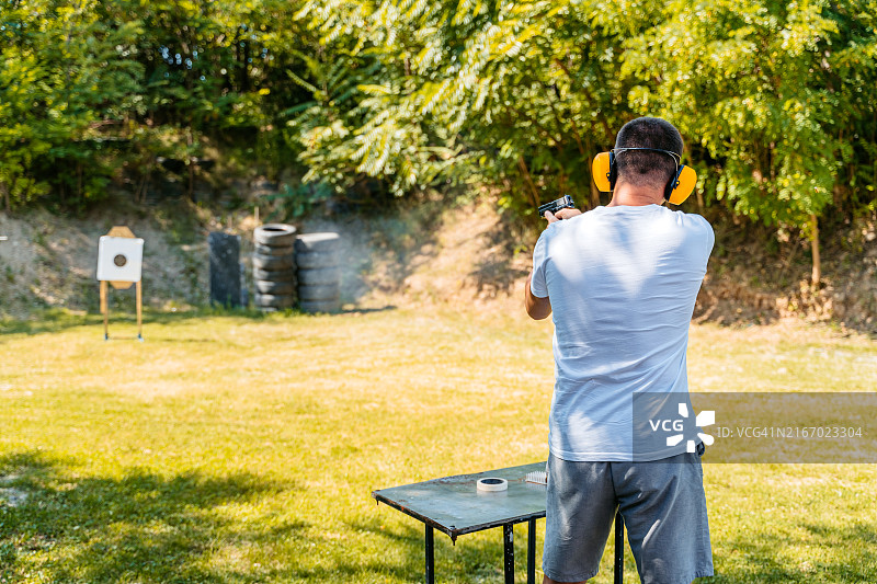 一名中年男子在户外射击场用手枪射击目标图片素材