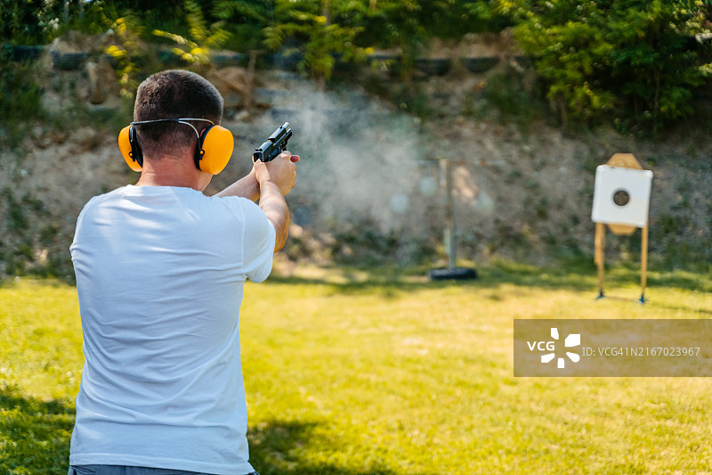 一名中年男子在户外射击场用手枪射击目标图片素材