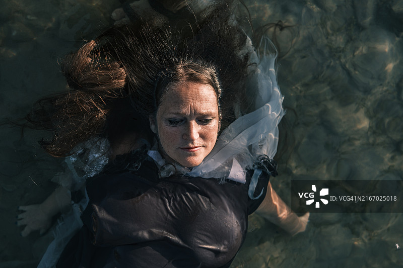 在海滩日落时分漂浮在水中的中年妇女图片素材