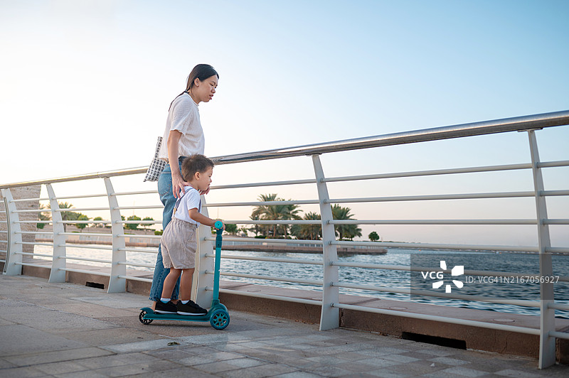 母子在海滨长廊骑滑板车图片素材