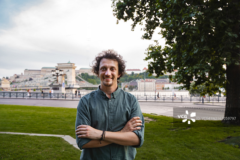 在阳光明媚的下午，微笑的男人在布达佩斯多瑙河畔摆姿势图片素材