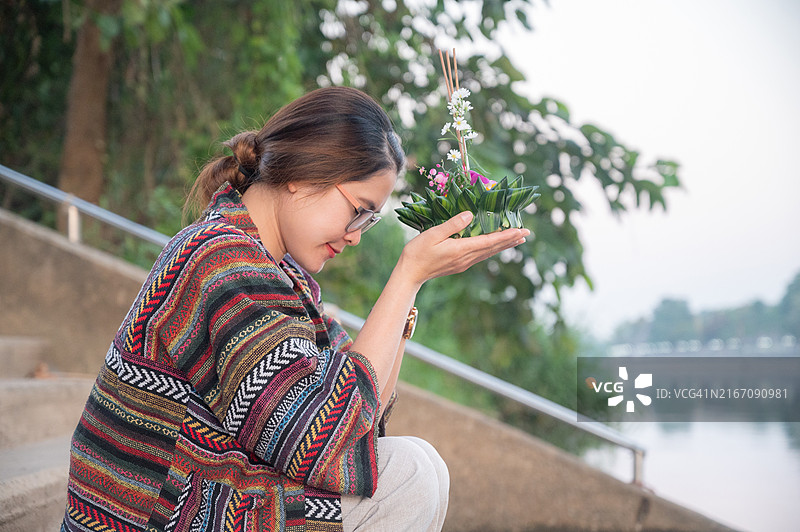 年轻的亚洲女性在泰国水灯节期间手捧水灯，祈祷水神图片素材